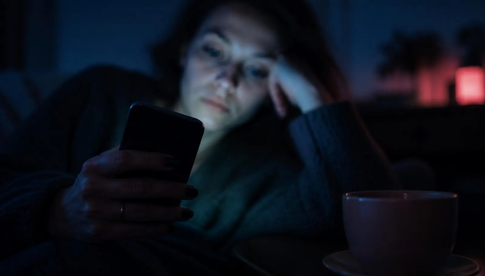 Une personne consultant son téléphone seule le soir, lumière bleue de l'écran